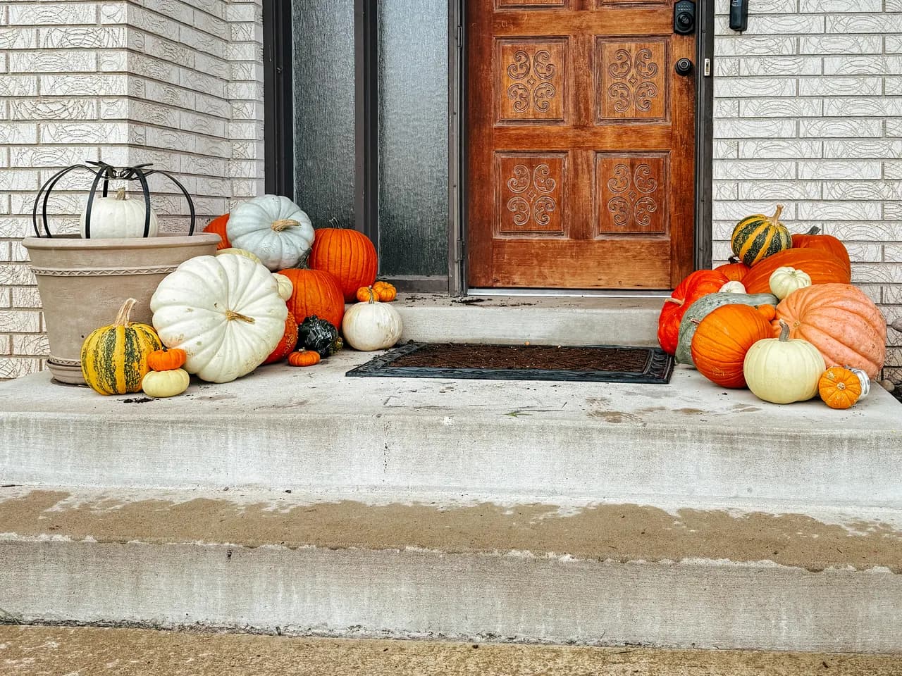 Ornate carved wood door flanked by Jarrahdale, Cinderella, and specialty pumpkins