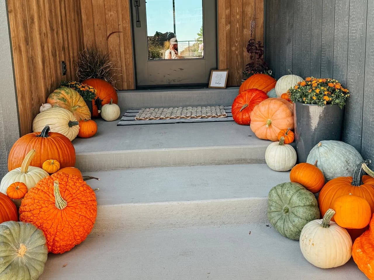 Gray board-and-batten home with full porch display including dried leaf wreath on door