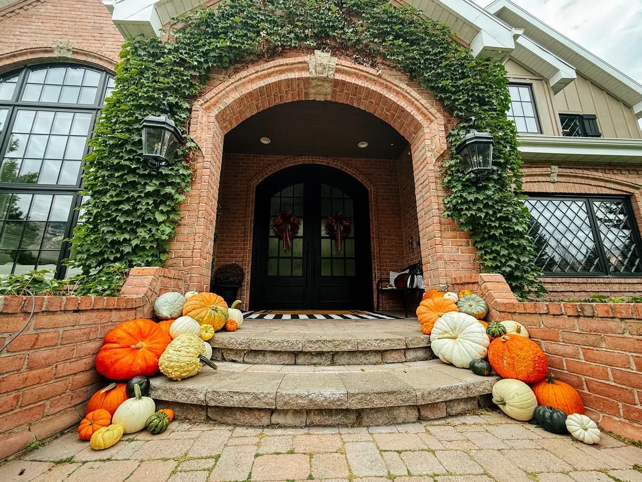 Brick and ivy arched entry with pumpkins cascading down stone steps — Grand level Entry Framing