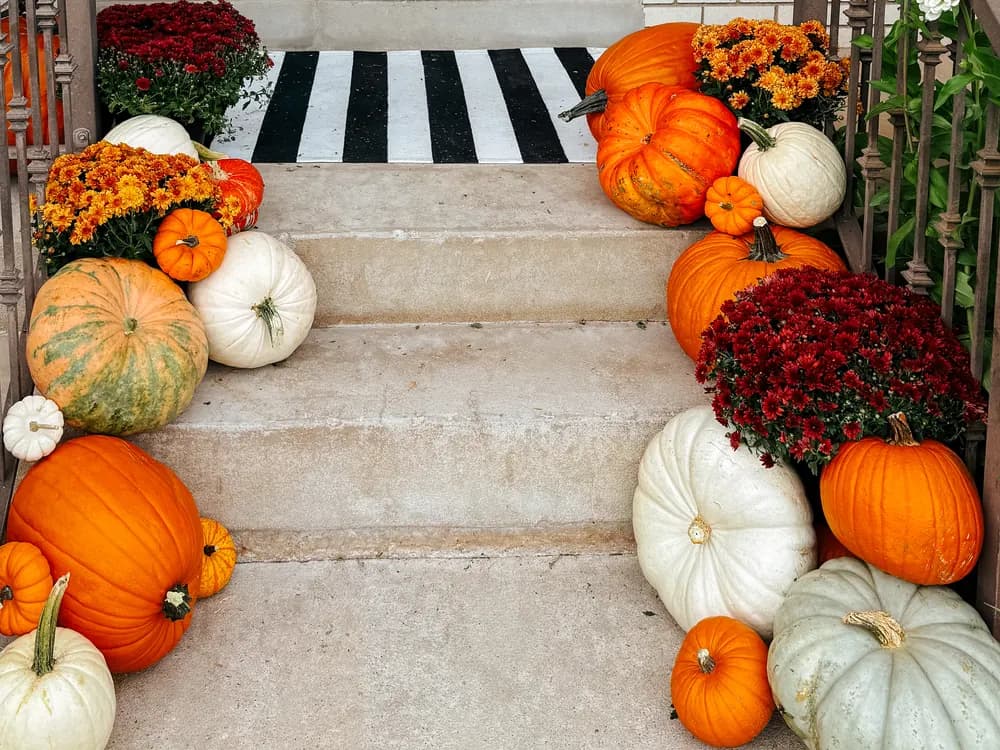 Blue door brick home with pumpkins symmetrically flanking the steps and a striped doormat